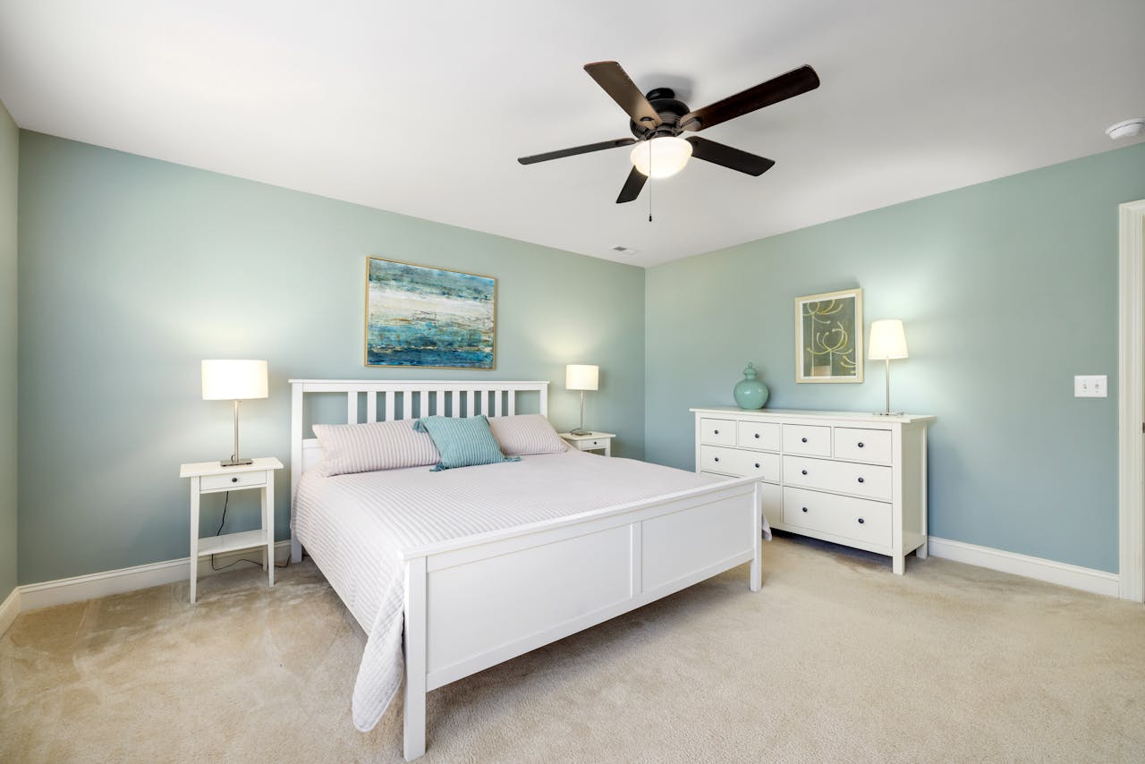 Services Clean and modern bedroom with minimalist decor, featuring pastel walls and white furniture.