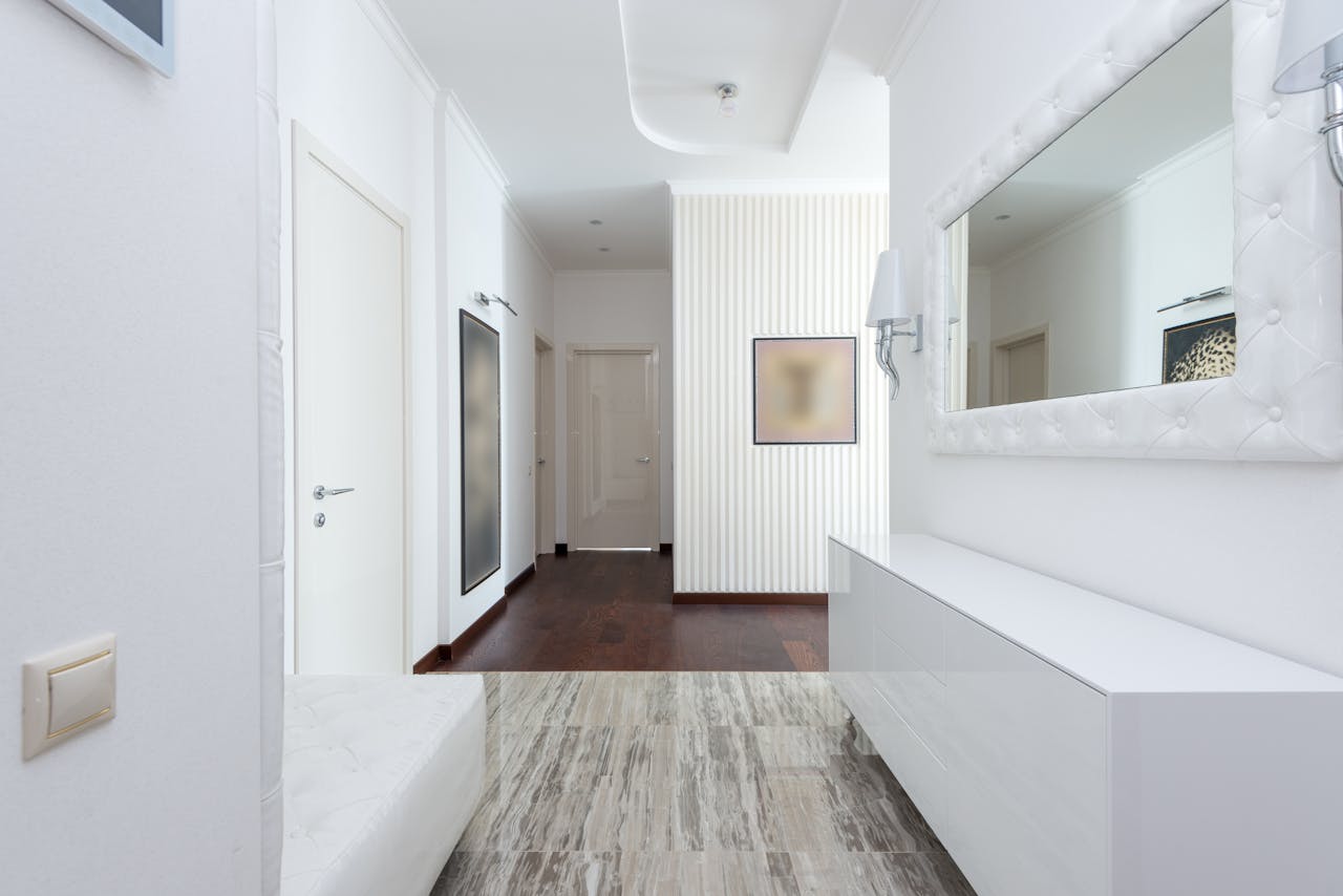 Home Bright corridor with contemporary design featuring white walls, minimal decor, and mirror.